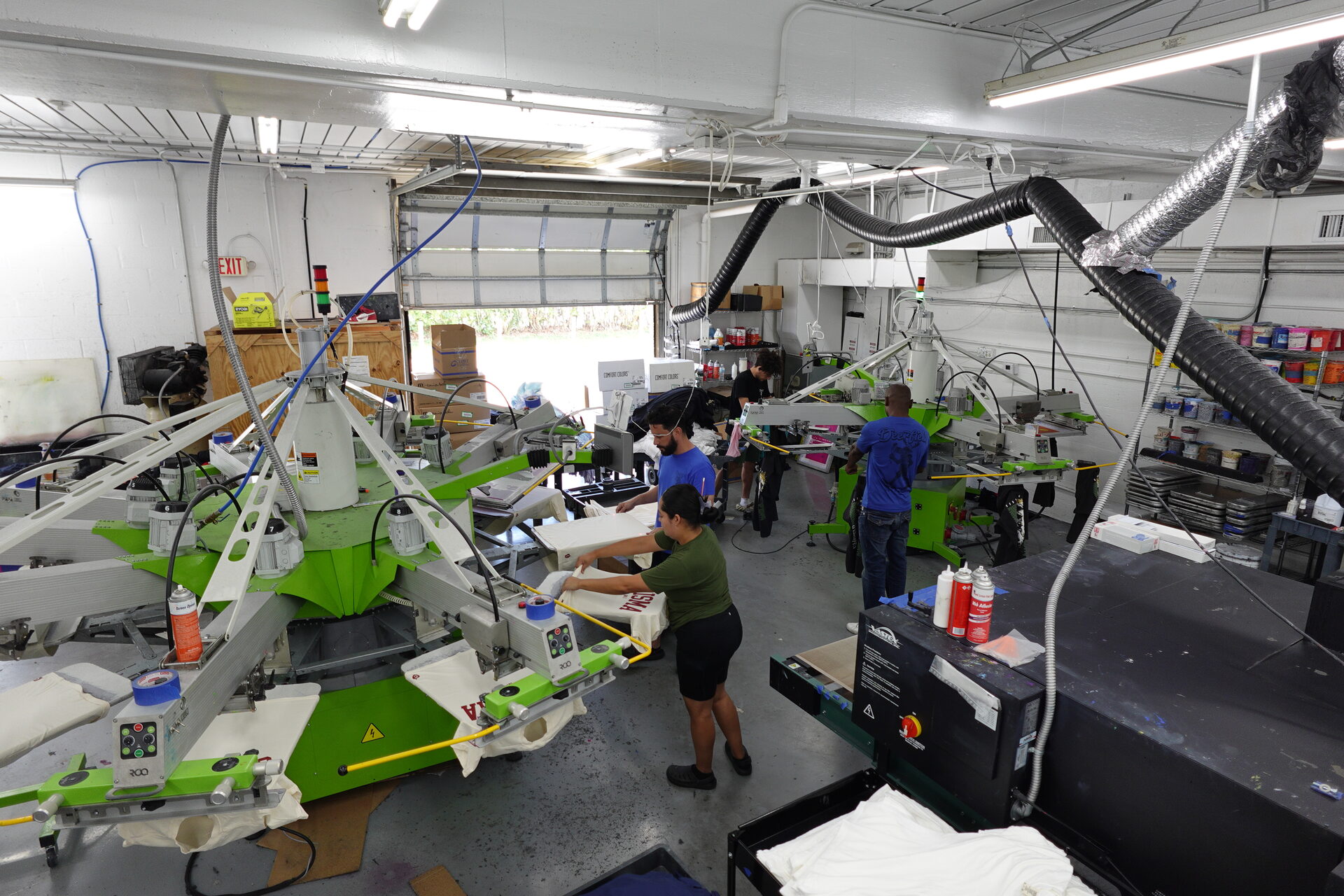 CustomPrintedShirts.com production floor with multiple ROQ automatic presses running and team operating the line